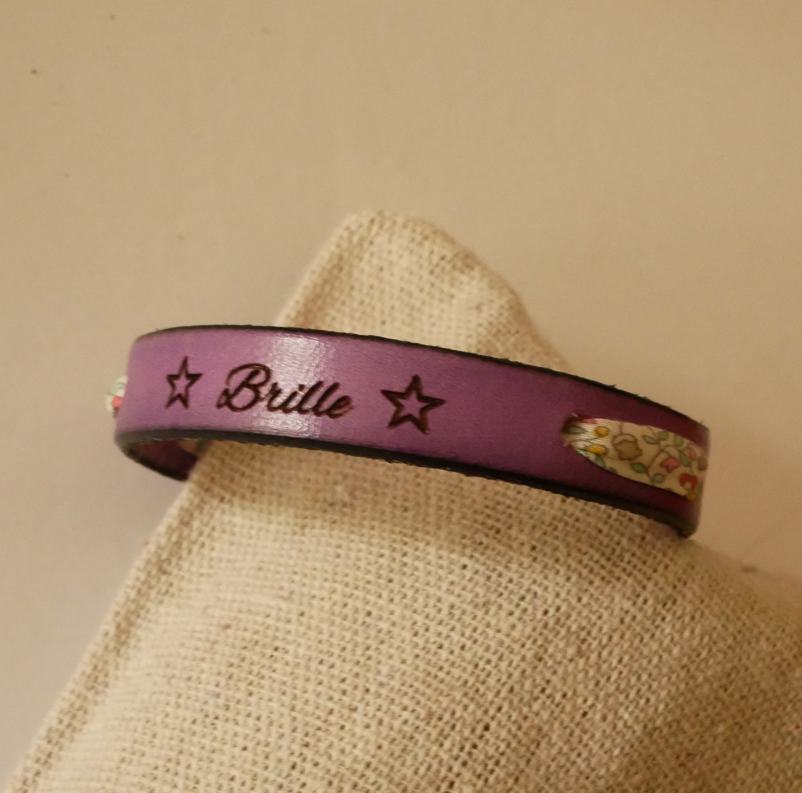 Pulsera Florâme "Brille" grabada con lazo liberty pastel sobre cuero morado