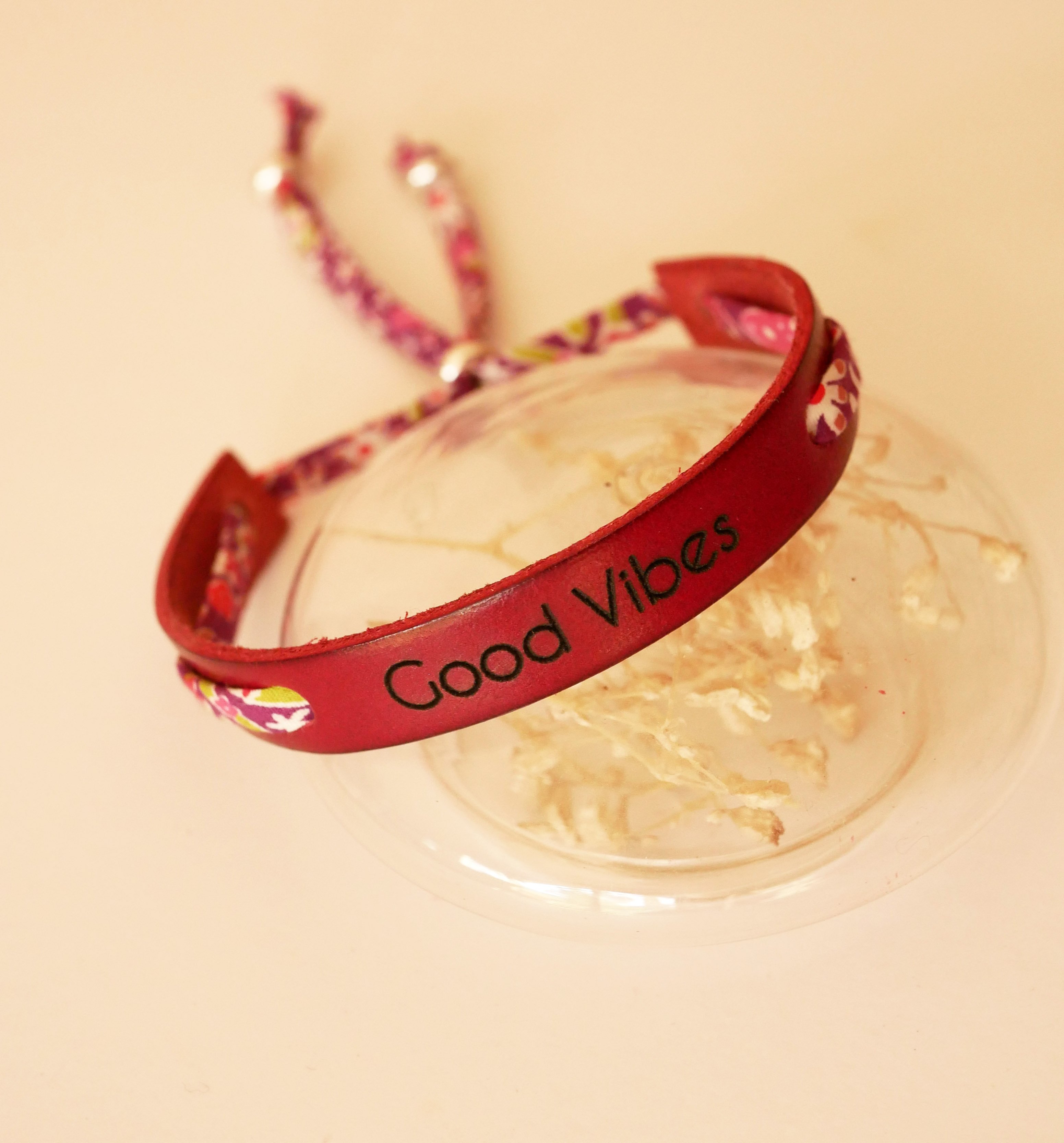 Florâme Pulsera Good vibes grabada con lazo liberty morado sobre piel roja