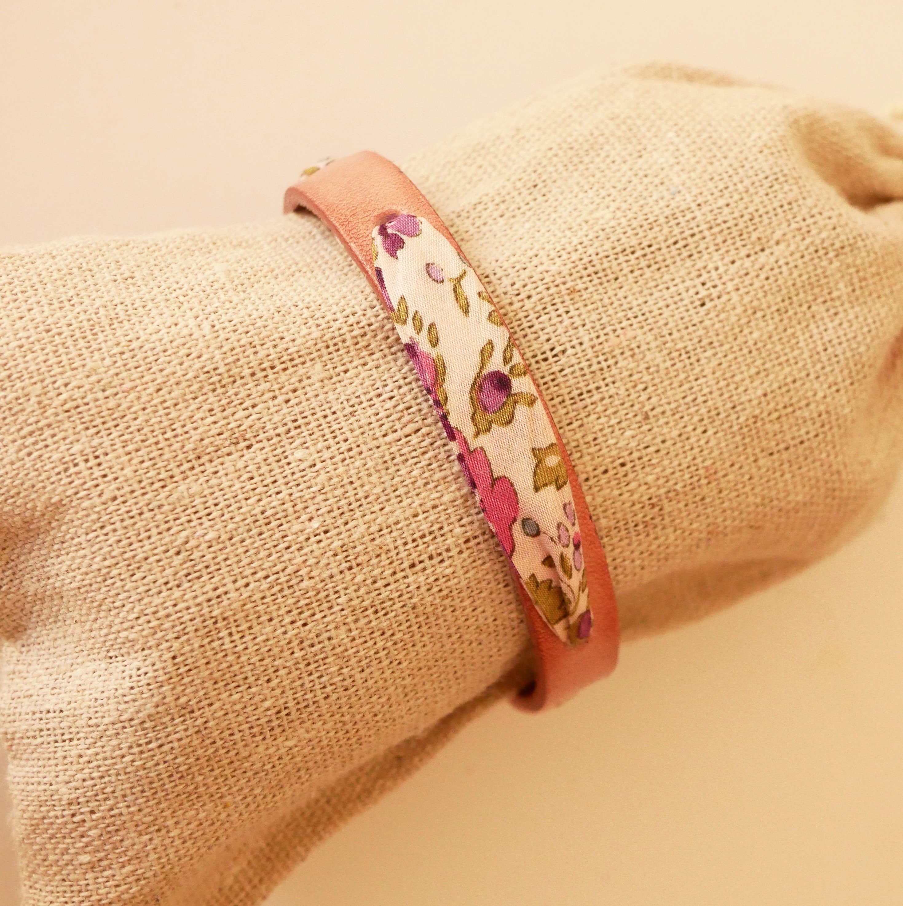 Pulsera Florâme con cinta liberty y flores moradas sobre cuero rosa envejecido