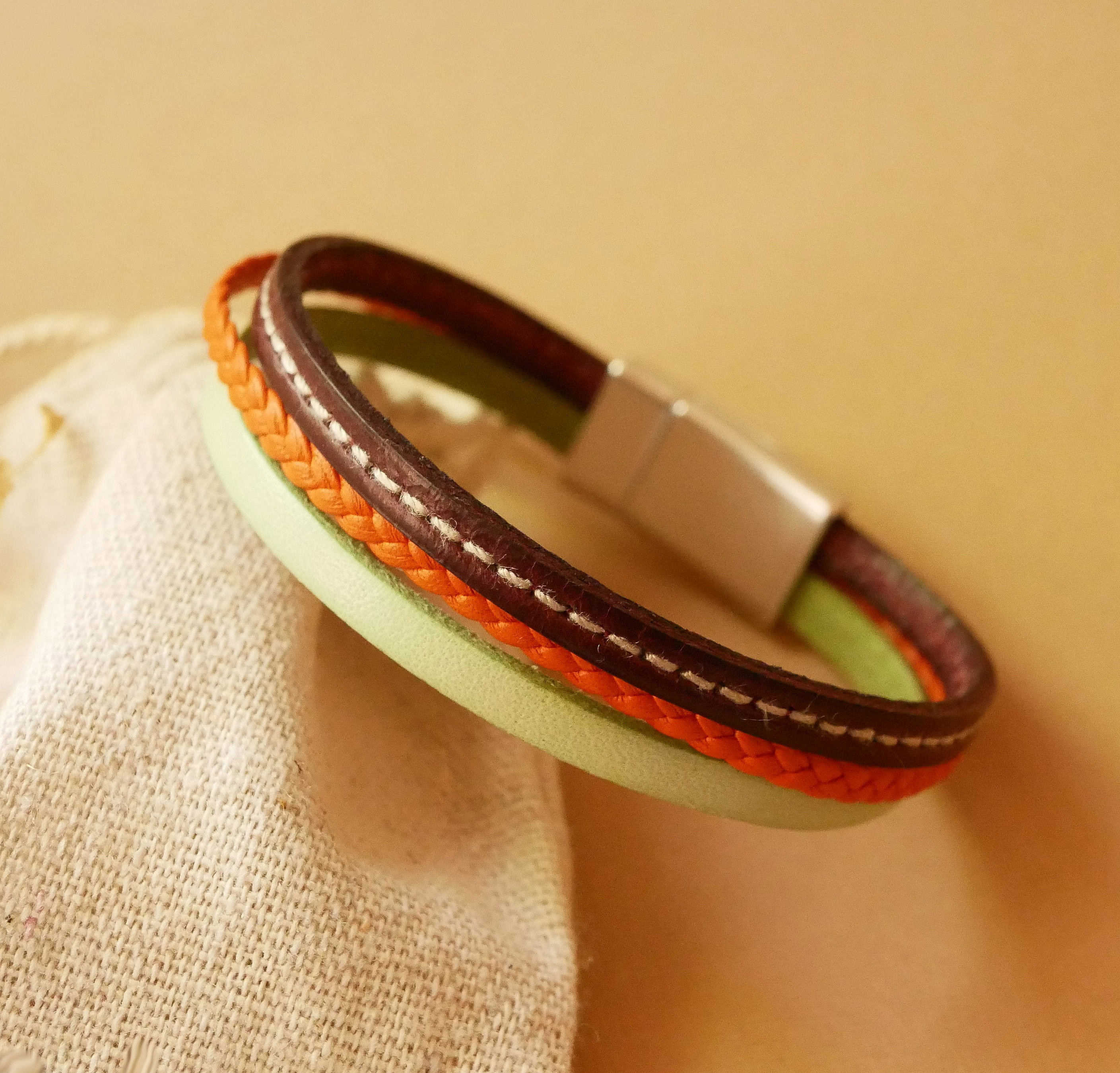 Pulsera brazalete multicuero con almendra, trenzado naranja y pespunte burdeos