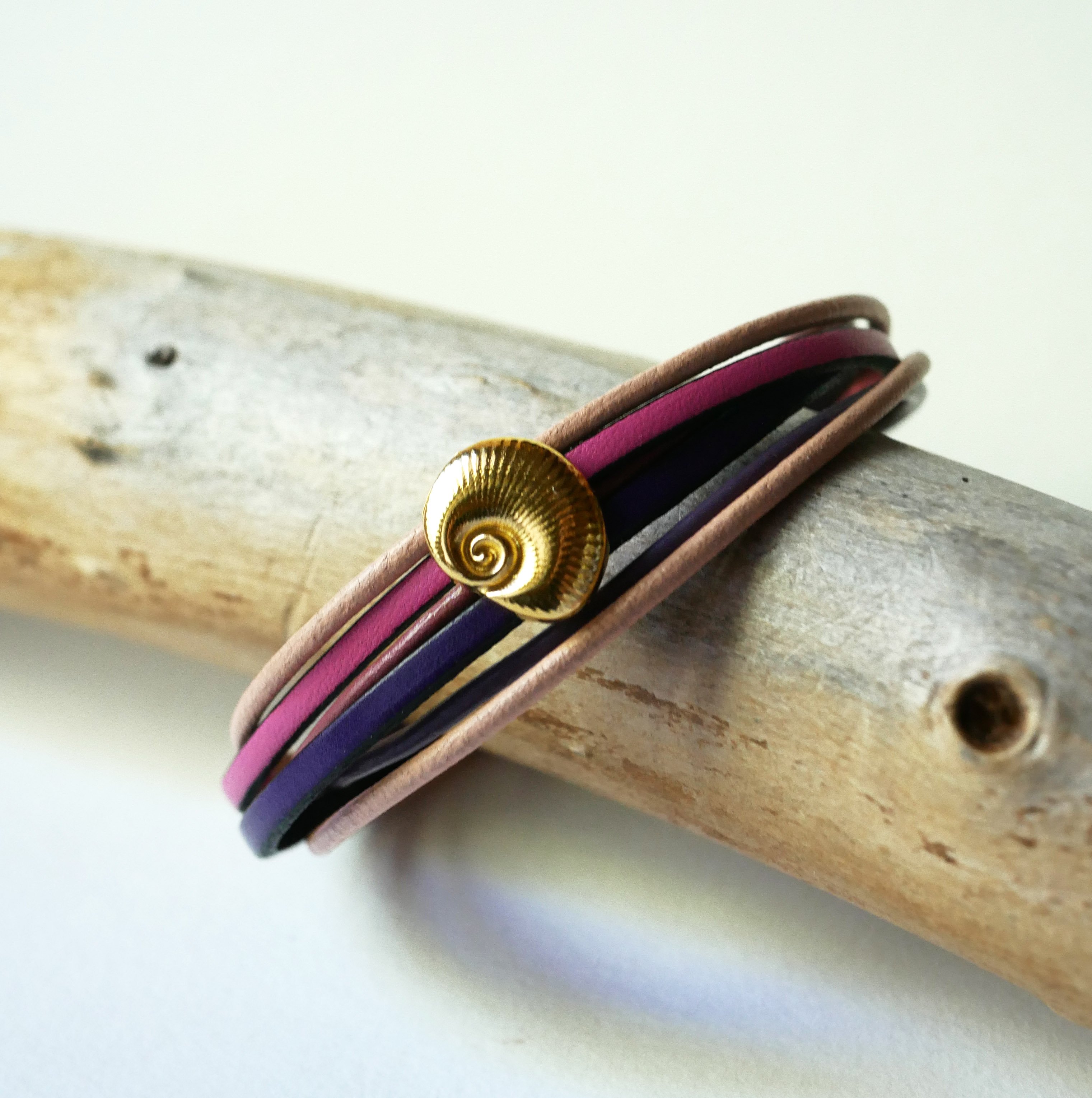 Pulsera de eslabones m&uacute;ltiples en pieles melocot&oacute;n y malva con adorno de concha dorada