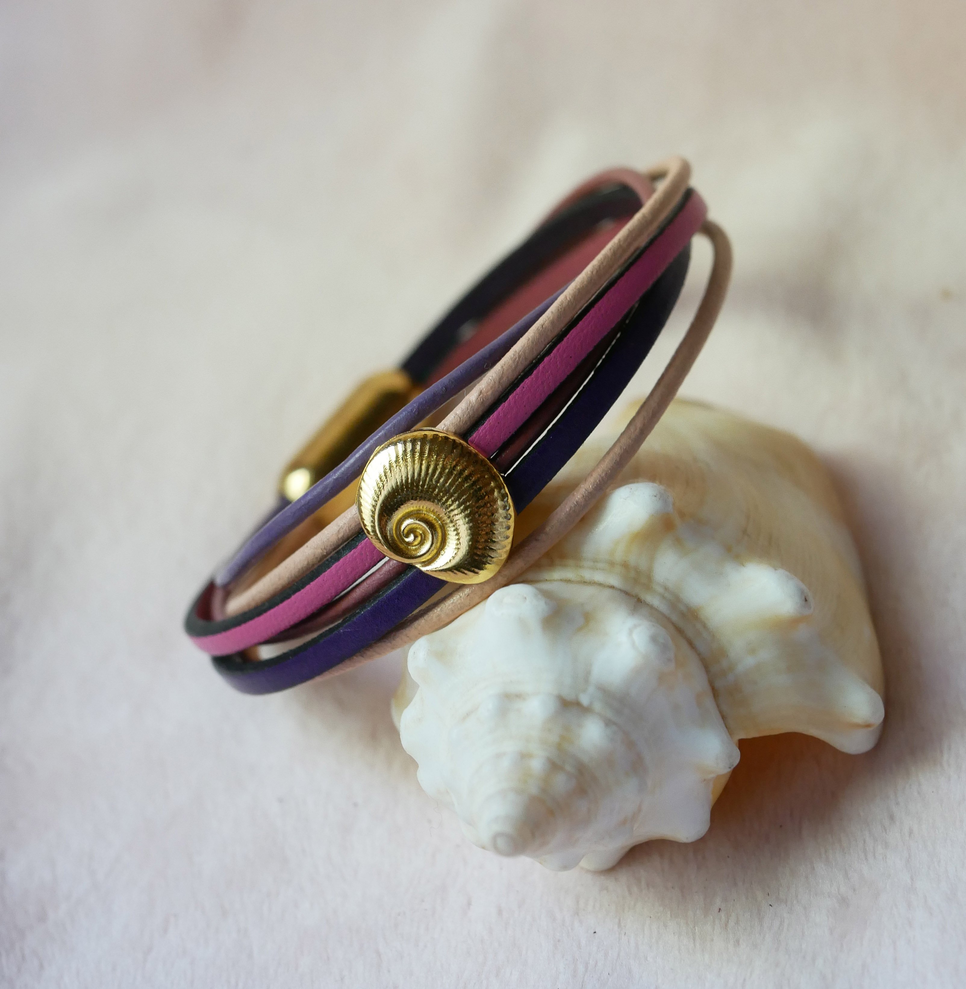 Pulsera de eslabones m&uacute;ltiples en pieles melocot&oacute;n y malva con adorno de concha dorada