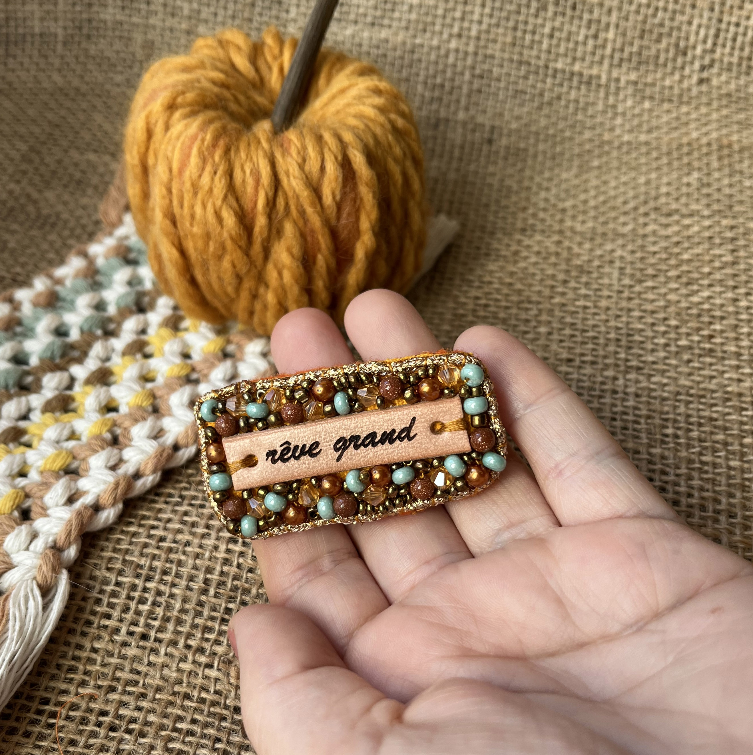 Broche en perles dorées à message en cuir gravé "rêve grand"