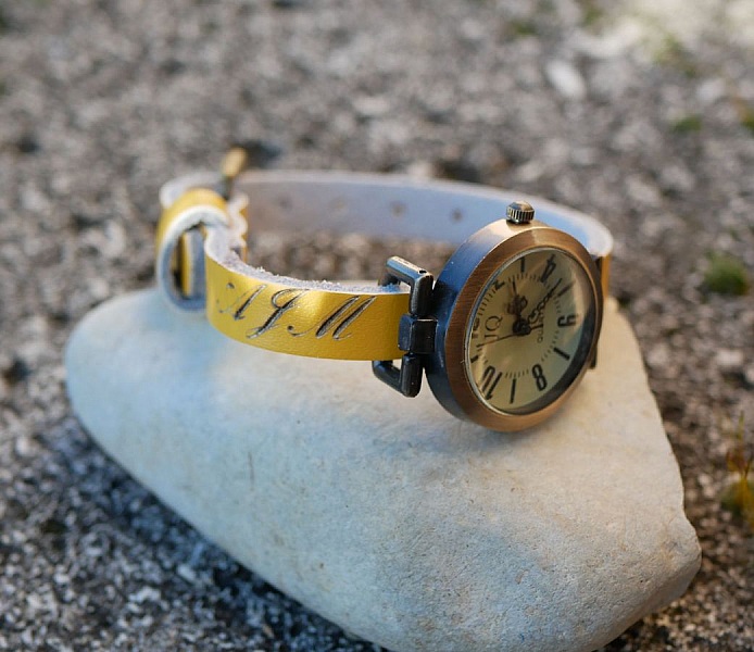 Montre personnalisée avec bracelet en cuir jaune gravé.