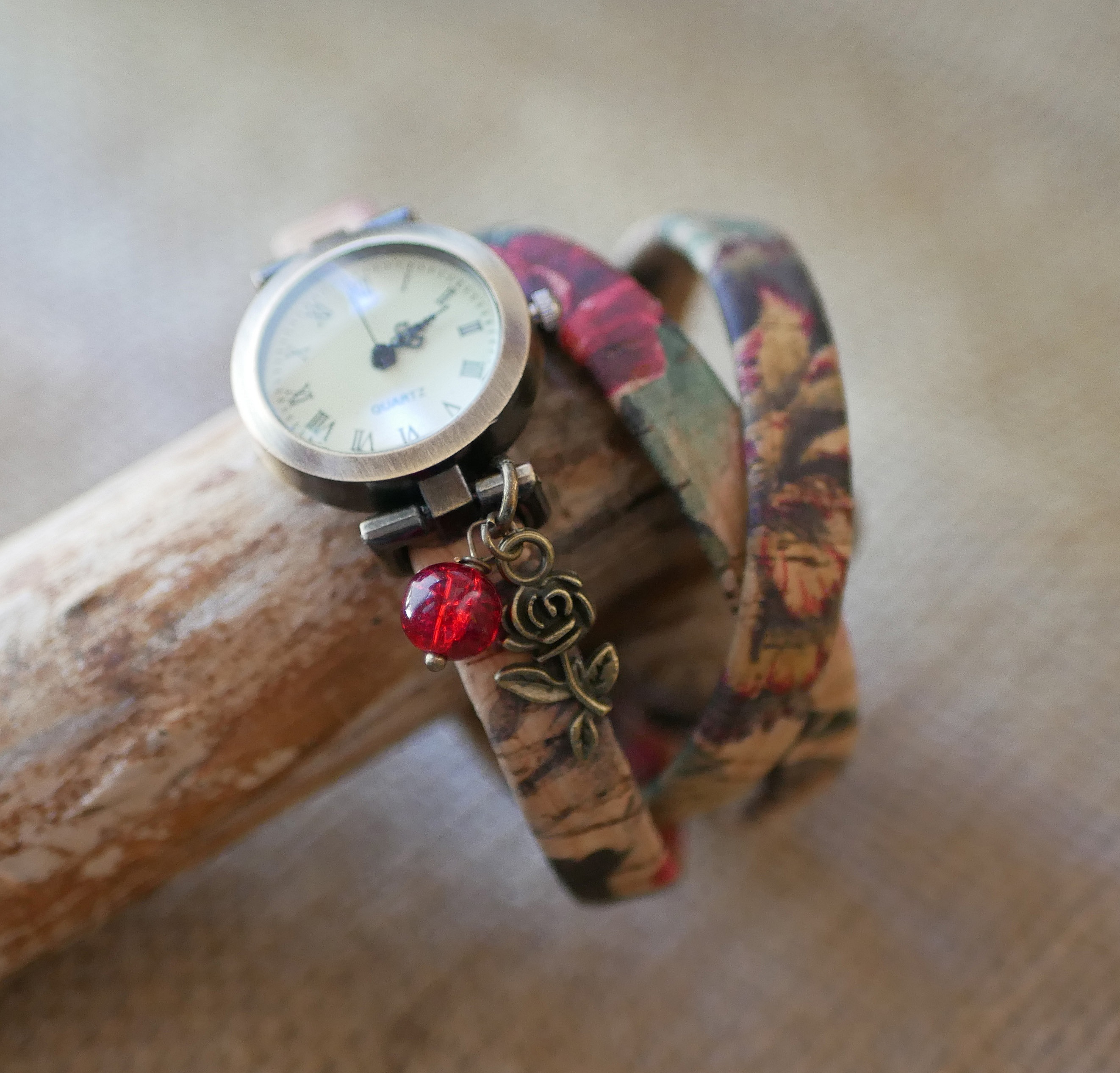 Montre bracelet personnalisable avec breloque rose et perle rouge.