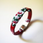Pulsera Florâme con cinta de cerezas sobre cuero rojo